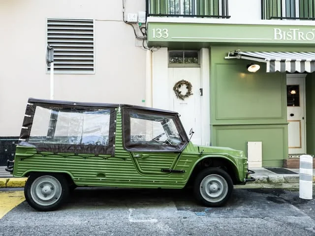 Citroën Méhari verte garée devant le 133, à côté de la porte de la façade verte