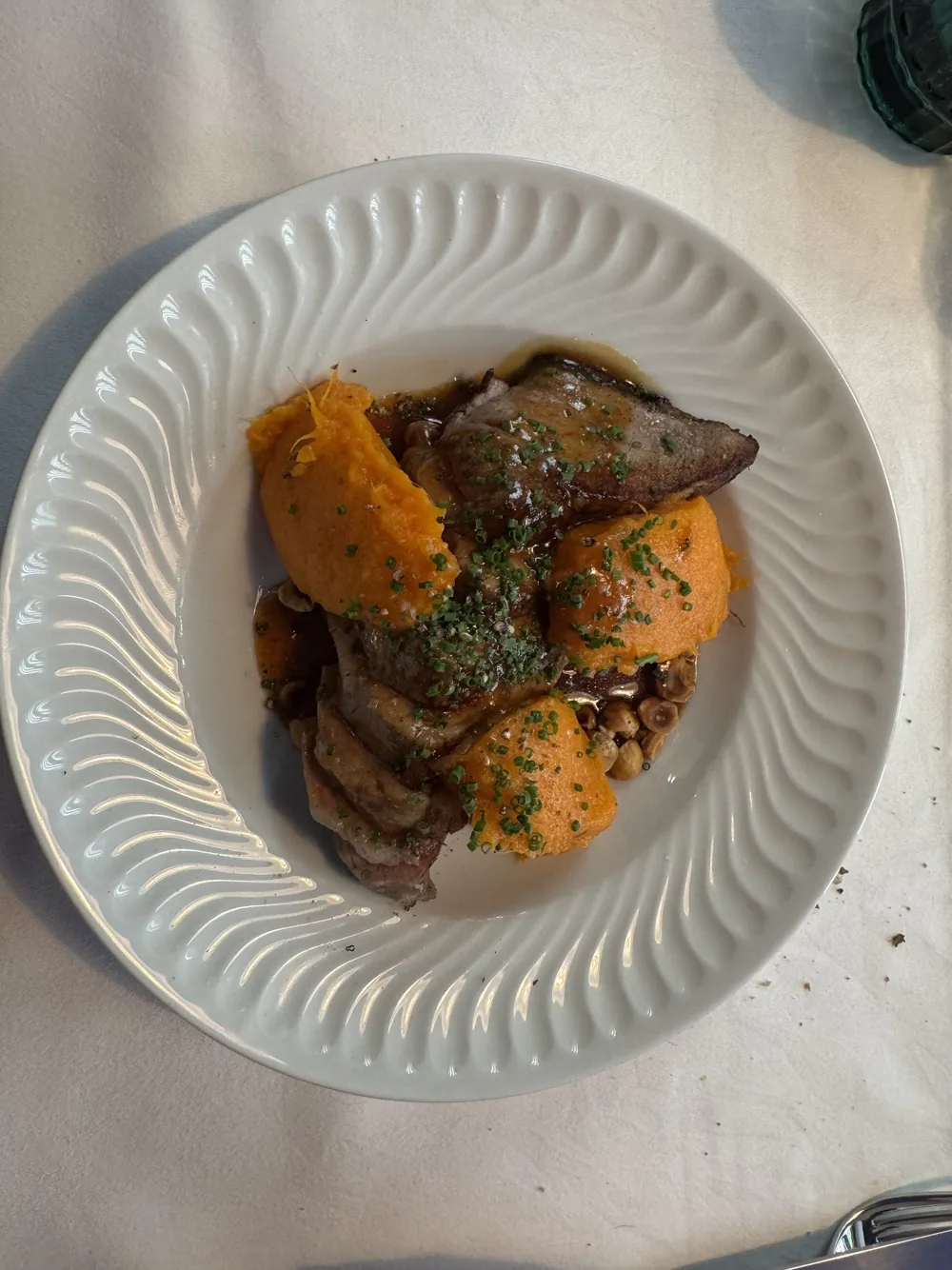 Viande confite et purée orange dans une assiette blanche cannelée